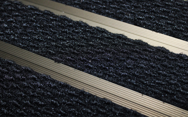 Close up image of Black Superguard inserts in Bronze ARCHIMAT aluminium architectural matting