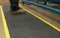 Insitu of someone in a warehouse standing on an OrthoStand mat which is an anti-fatigue rubber mat