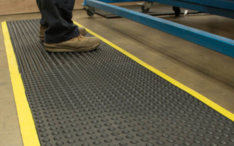 Insitu of someone in a warehouse standing on an OrthoStand mat which is an anti-fatigue rubber mat